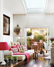 a chic neutral living room with touches of pink, an artwork and a cool pendant lamp