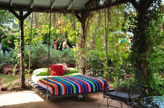 a dark stained wooden hanging bed with ropes and colorful bedding to remind that this is summer