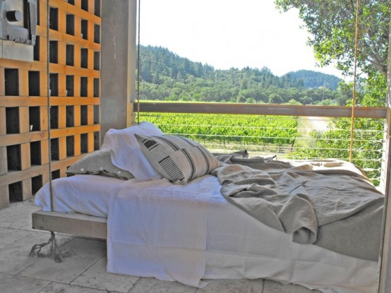 a whitewashed hanging bed on ropes with bedding, pillows on a balcony is a cool idea to have a nap outside