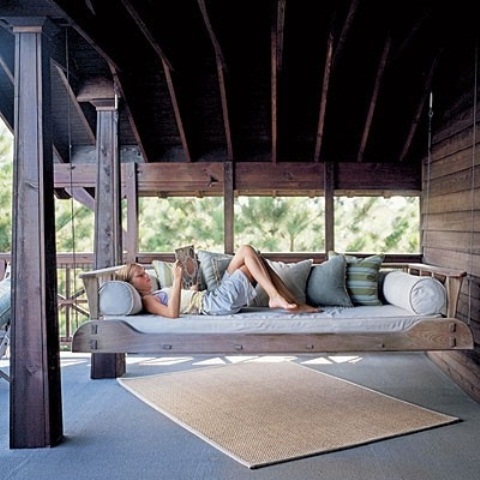 a whitewashed wooden hanging bench with pillows and cushions is a comfy rustic idea for any outdoor space