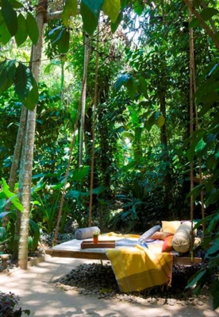 a wooden hanging bed on ropes with colorful bedding and pillows is a cool idea with a relaxed boho feel