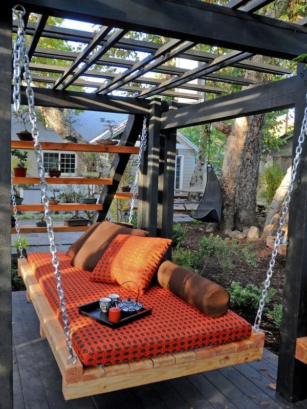 a black gazebo with a hanging bed on chains, with colorful cushions and pillows for a zen feel and meditative practice