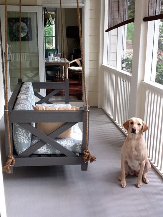 a rustic grey hanging daybed with ropes and printed bedding is a great fit for a rustic or vintage space