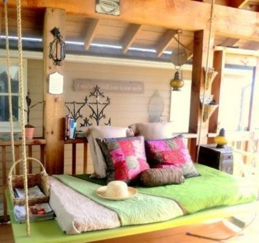 a green outdoor hanging bed on ropes features not only a seat but also some space for storage