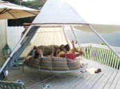 a round hanging bed on ropes with pillows for several people and a tent on top to enjoy fresh air even when it’s raining