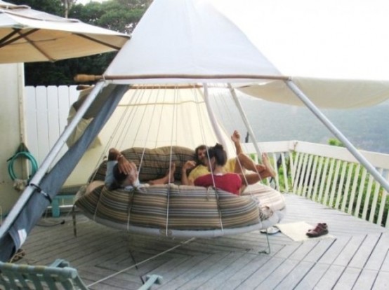 a round hanging bed on ropes with pillows for several people and a tent on top to enjoy fresh air even when it's raining