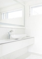 a fresh Nordic bathroom with a long sleek vanity, a large mirror and a bowl sink