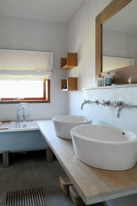 a relaxed Scandinavian bathroom with a blue vintage tub, large bowl sinks and a large mirror