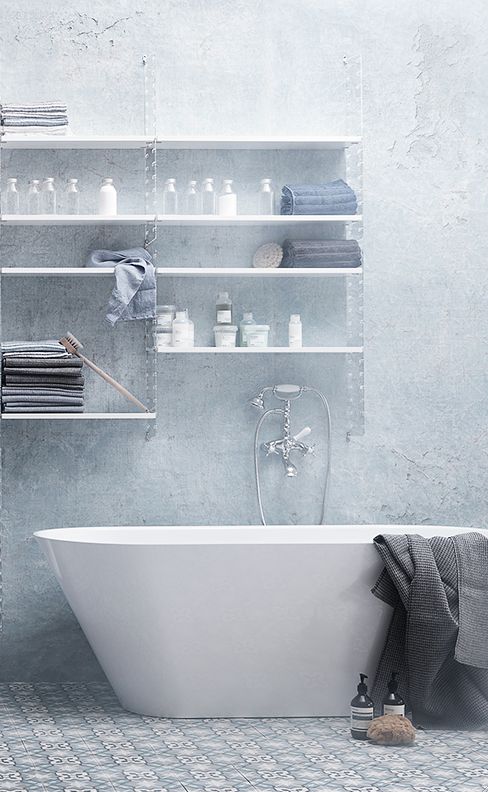 an off-white and grey bathroom with mosaic tiles on the floor, a tub and a large open shelving unit