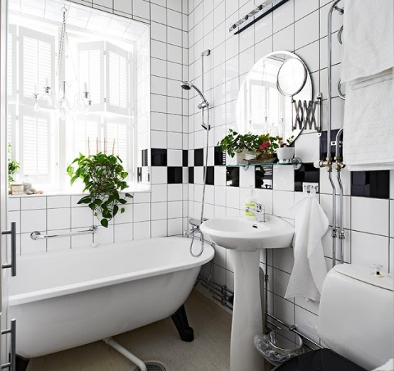 a Nordic bathroom with a retro feel done in black and white, with potted greenery for a fresh touch and a vintage bathtub