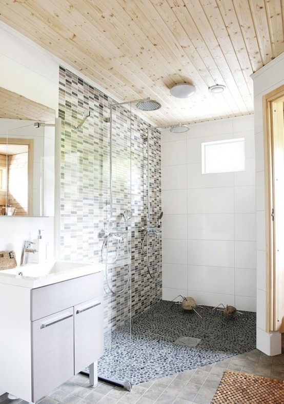 a neutral Nordic bathroom with a wooden ceiling, a mosaic tile wall and a pebble floor and an off-white vanity