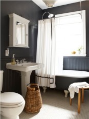 a black and white Scandinavian bathroom with a vintage tub, a stool, a basket and a vintage mirror