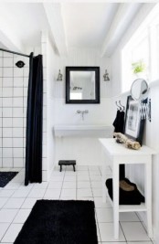 a simple Nordic black and white bathroom with black textiles, white tiles with black grout and white furniture