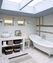 a neutral Nordic bathroom with skylights, a vanity with storage boxes and a vintage tub