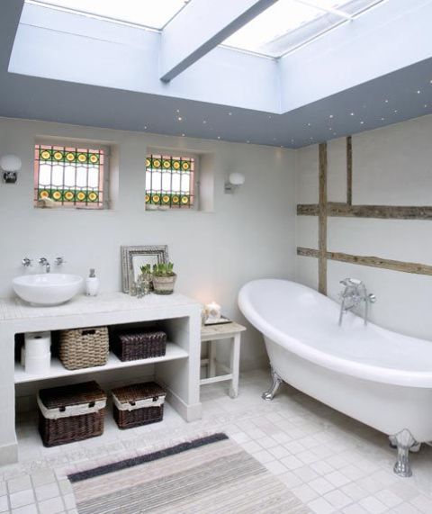 a neutral Nordic bathroom with skylights, a vanity with storage boxes and a vintage tub