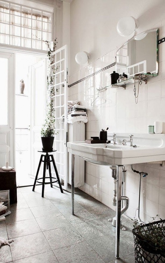 a vintage Nordic bathroom with a large sink, potted greenery, much natural light and a mirror with a shelf