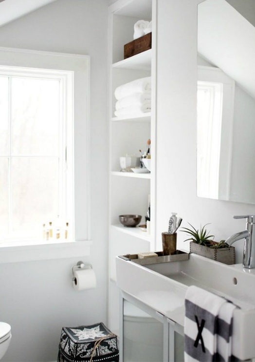 a neutral Scandinavian bathroom done with a wooden planter, a striped towel and a Moroccan ottoman