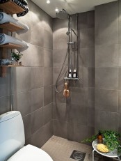 a grey Scandinavian bathroom with an open shelving unit, potted greenery and a small shower space