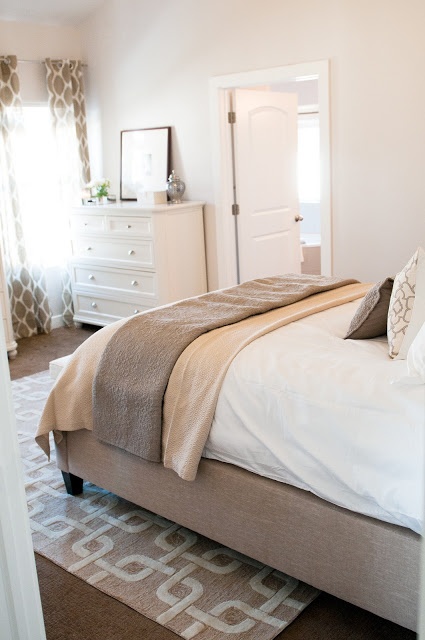 a neutral bedroom with an upholstered bed, printed textiles, simple and chic furniture is very welcoming