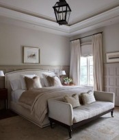 a refined and chic bedroom in neutrals, with stylish furniture, blush linens and an elegant pendant lamp