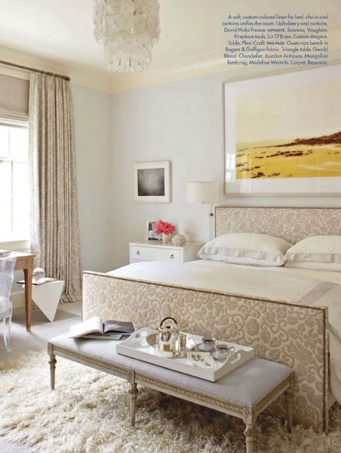 a neutral and refined feminine bedroom with printed textiles, a fluffy rug and a chic chandelier and a bench