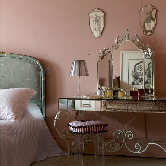 a pink French-style boudoir bedroom with a blue floral bed, elegant vanity and a stool and some antique mirrors is lovely