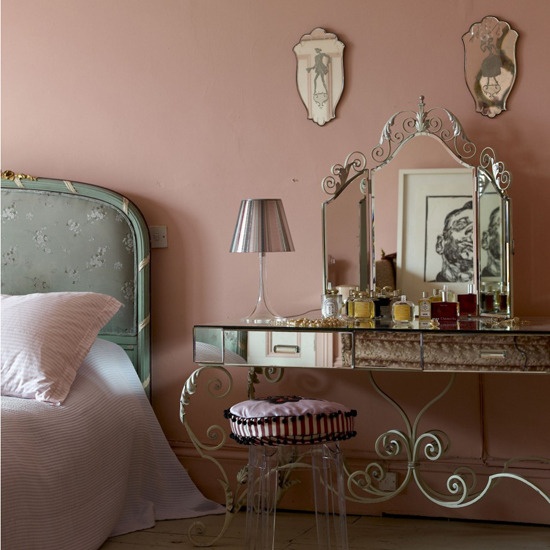 a pink French-style boudoir bedroom with a blue floral bed, elegant vanity and a stool and some antique mirrors is lovely