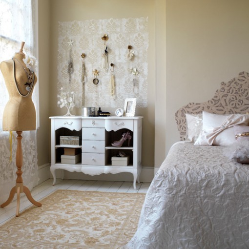 a neutral vintage bedroom with warm-colored walls, a pretty patterned bed, a dresser with accessories and a mannequin as decor is very Parisian-style