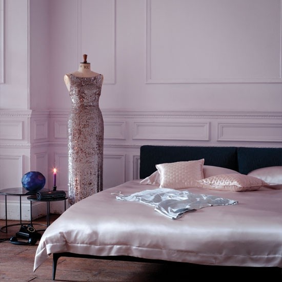 a refined modern bedroom with blush paneled walls, a black bed with blush silk bedding and a mannequin with a refined blush sequin dress
