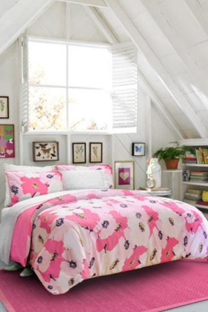 a bright attic bedroom with neutral furniture, bookshelves, a gallery wall and a bed with bright pink bedding