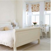 an airy feminine bedroom with elegant neutral furniture, refined lamps and accessories and floral Roman shades for an accent
