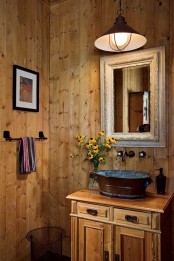 a simple stained wood barn bathroom with a wooden vanity, with a mirror in a frame and a vintage pendant lamp