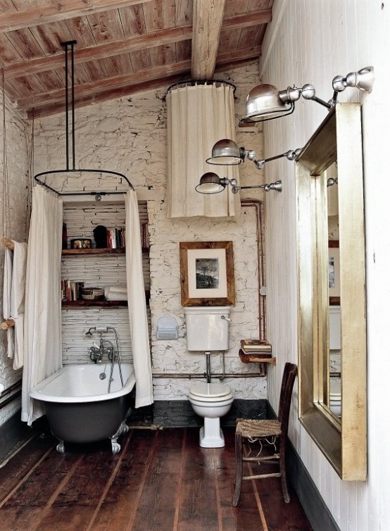 a white barn bathroom with stone walls, a wooden ceiling, wooden planks on the wall and a vintage clawfoot tub with a canopy