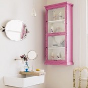 a chic guest toilet with a pink storage unit, a wall-mounted sink and some mirrors