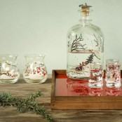 red and white Christmas candleholders and a bottle with a Christmas scene with evergreens