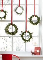 a whole arrangement of evergreen wreaths hanging on red ribbons for a chic and natural Scandinavian feel