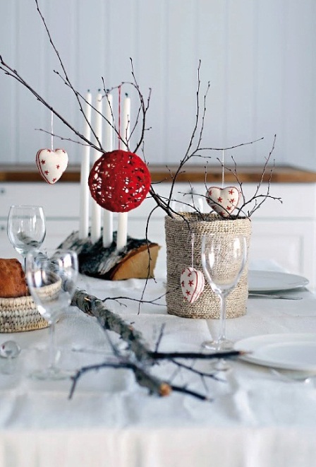 a fun Christmas centerpiece with a burlap wrapped tin can and branches plus a red yarn ball and heart-shaped fabric ornaments