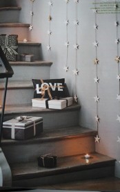 gift boxes and candles right on the steps and star garlands on the wall for a cozy Christmas feel