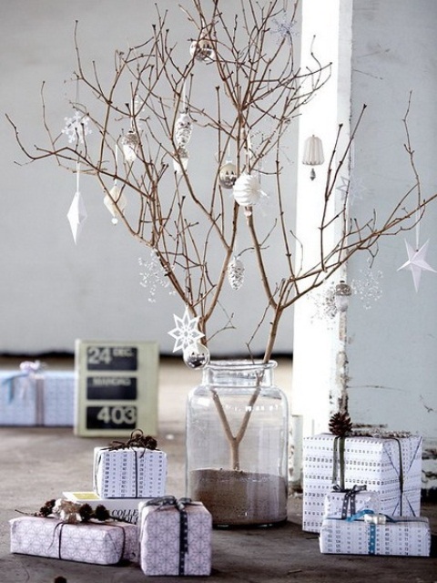 a branch Christmas centerpiece with white ornaments of paper and glass and neutral gift boxes