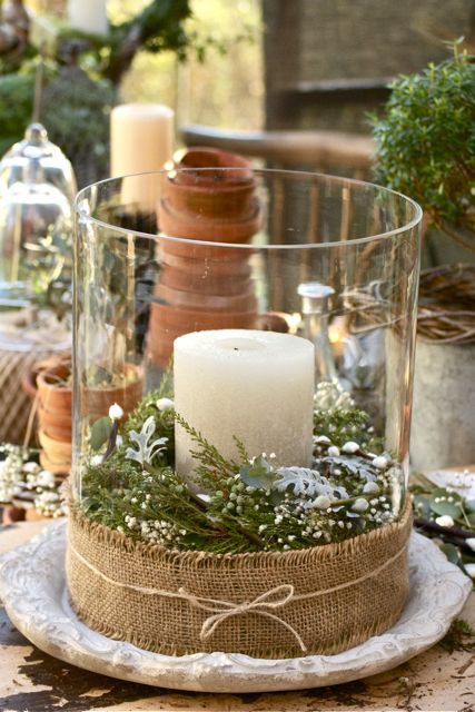 a glass jar wrapped in burlap, with evergreens inside and a candle for a cozy rustic Christmas feel