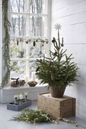 Nordic Christmas decor with an evergreen tree with pinecones in a basket, a pinecone and candle chandelier, greenery, lights and bulbs