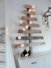 a simple Christmas tree made of reclaimed wood and decorated with lights is a veyr rustic and Nordic idea