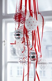 a cluster of white and silver Christmas ornaments hanging on red ribbons for a Scandinavian feel