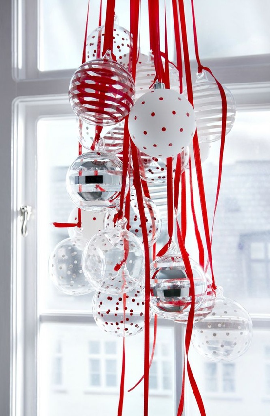 a cluster of white and silver Christmas ornaments hanging on red ribbons for a Scandinavian feel