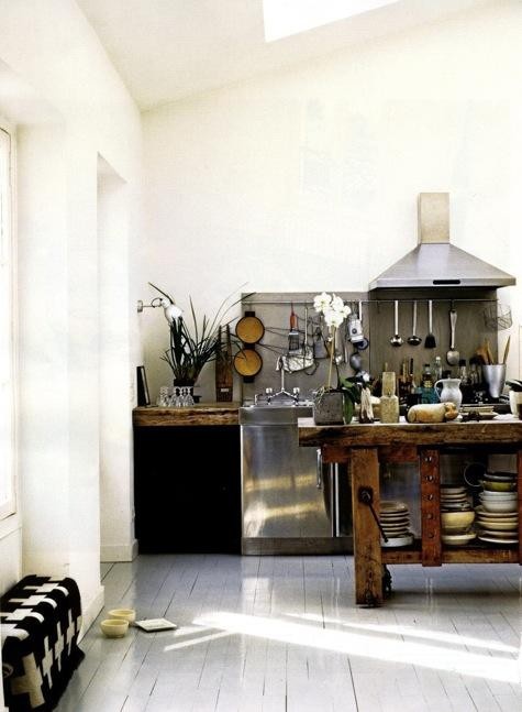 a vintage Scandinavian kitchen with a whitewashed floor and white walls, a rough wood kitchen island, touches of metal and rough wood