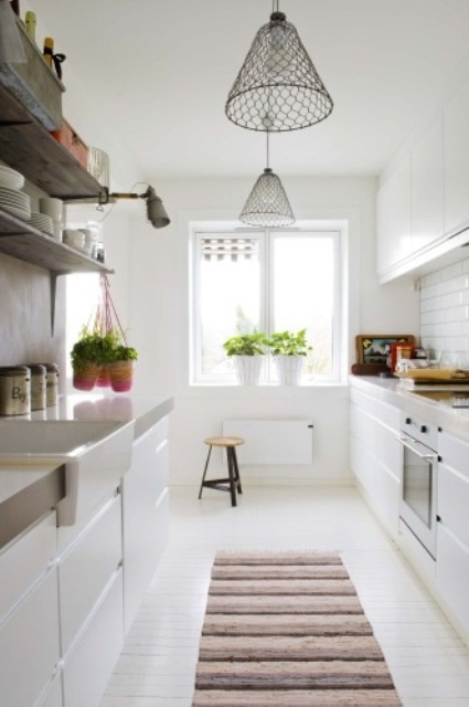 a modern white Scandinavian kitchen with sleek cabinets, mesh pendant lamps and a striped rug