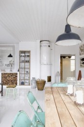 a Nordic kitchen with a wooden table, mint chairs, vintage pendant lamps, a stove and a built-in buffet