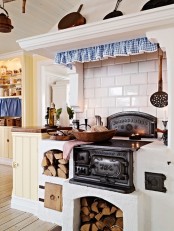 a retro Nordic kitchen with a stove, firewood, white subway tiles, buttermilk cabinets and touches of blue