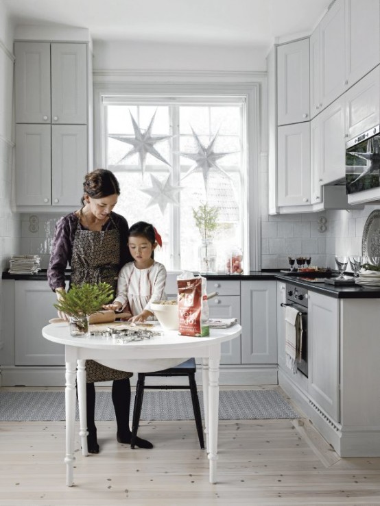 a neutral Nordic kitchen with vintage cabinets, stars hanging on the window, a round table