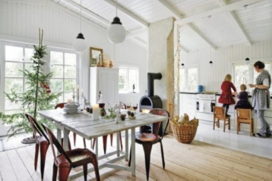 a white Scandinavian kitchen with a whitewashed table, white cabinets, a fireplace and pendant lamps